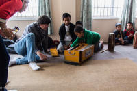 kids at an orphanage in the Kathmandu Valley explaining traditional Asian instruments to tour members